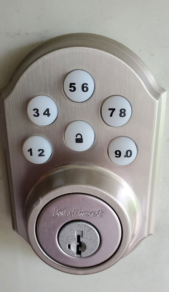 A silver Kwickset number door lock. The numbers are white soft push buttons and go from 0 to 9