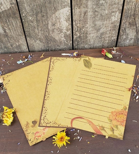 3 pieces of natural paper stationary on a wooden table with dried flowers sprinkled around