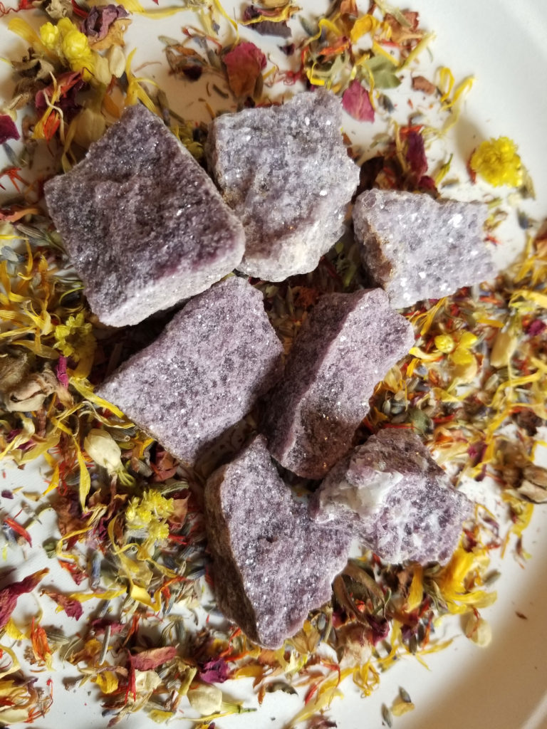 Several pieces of Lepidolite stones with dried herbs