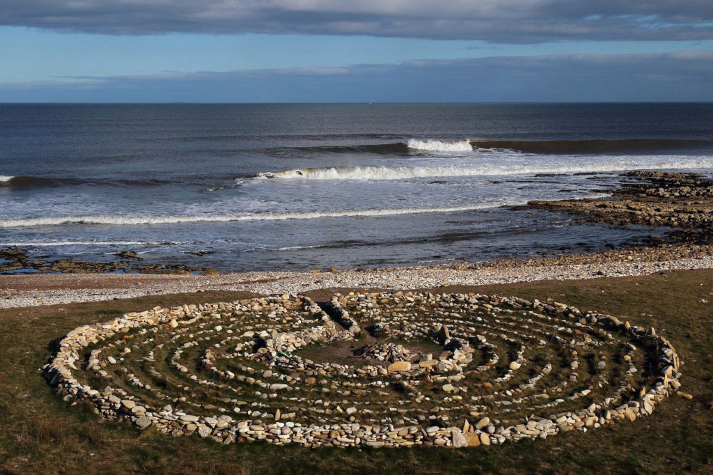 A photo of a large walking labyrinth in front of the ocean